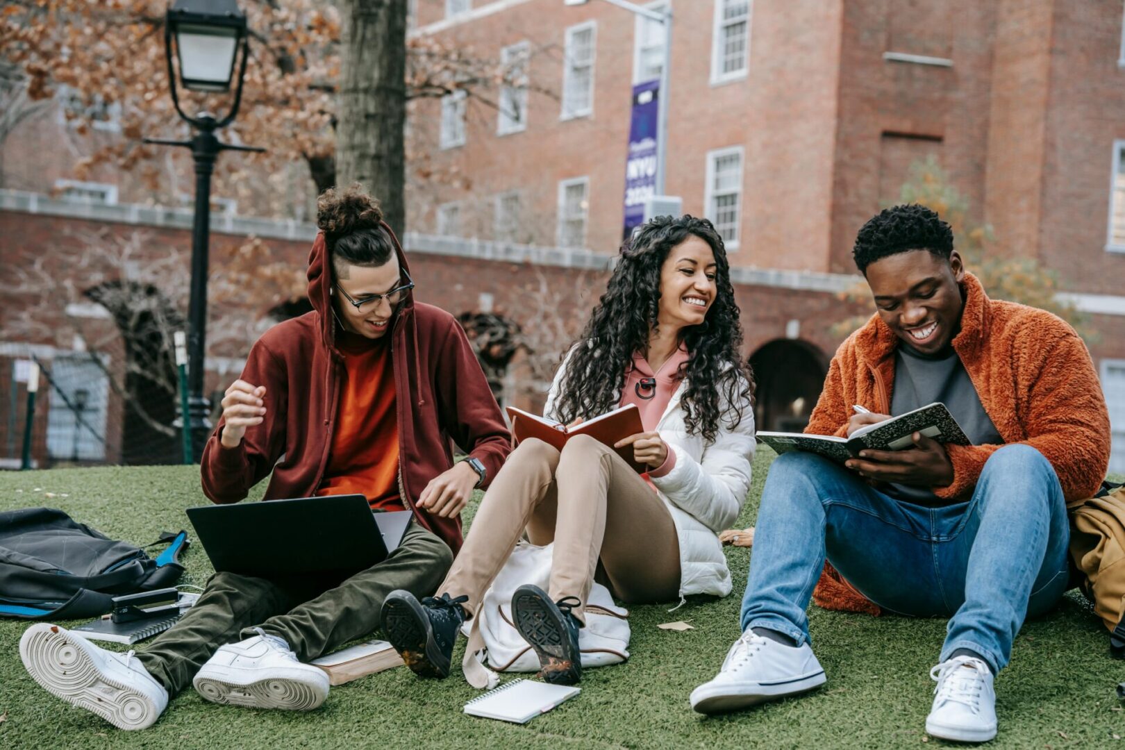 A group of people sitting on the grass with books