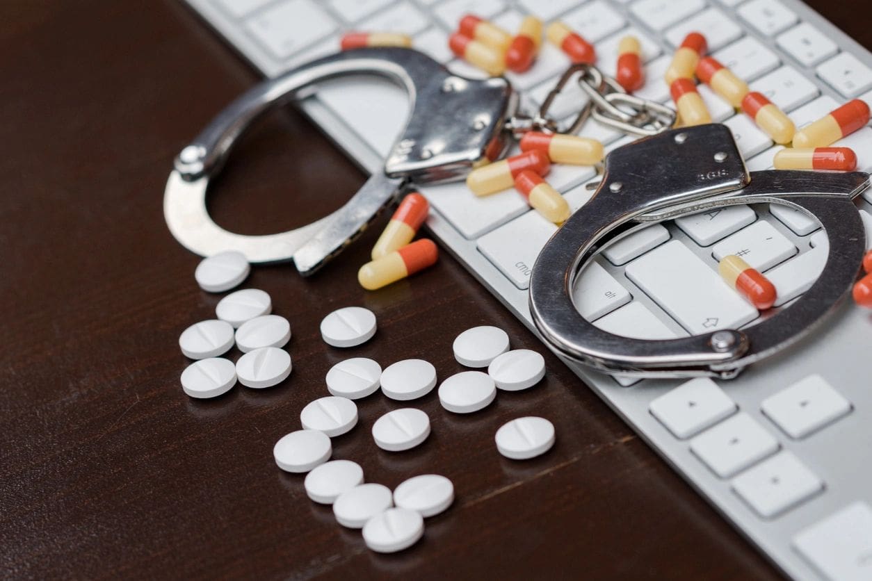 A pair of handcuffs and pills on the table.