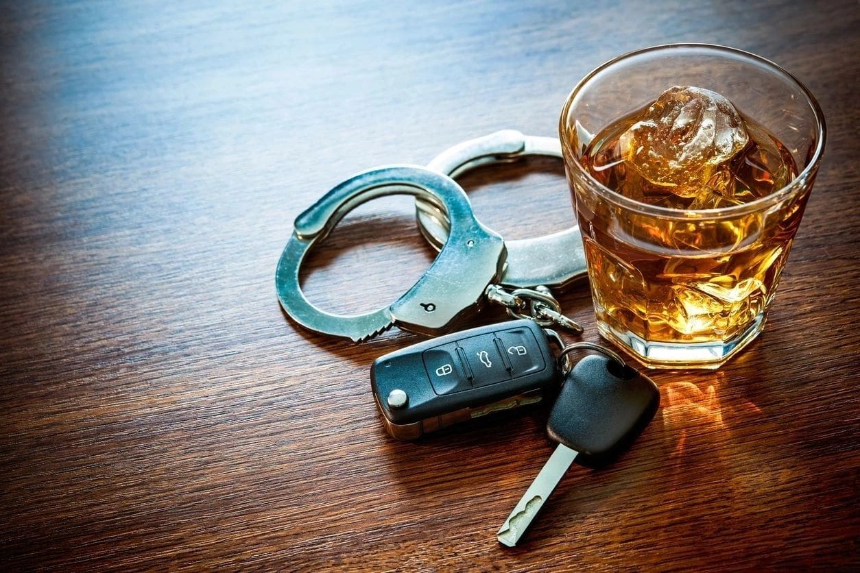 A glass of alcohol and car keys on the table.