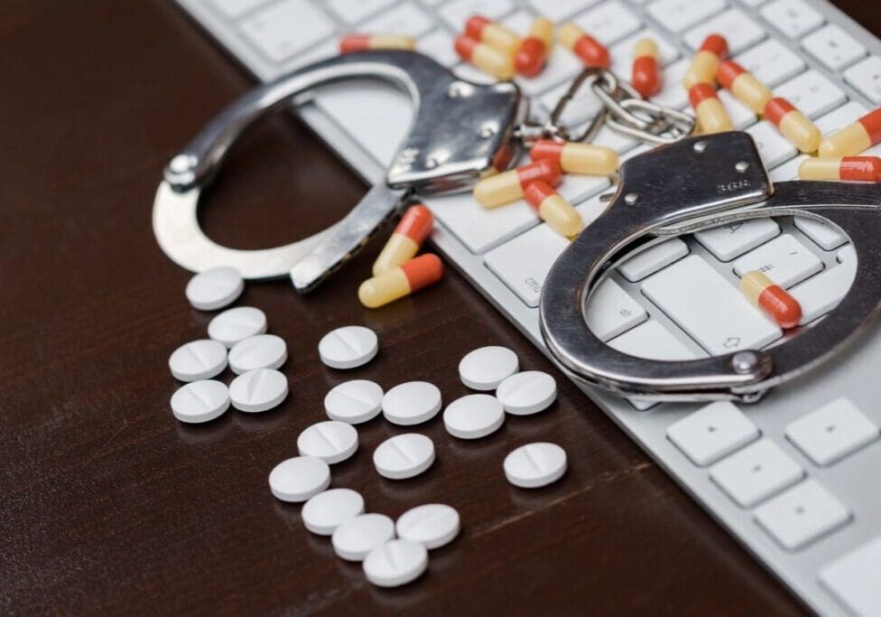 A pair of handcuffs and pills on the table.